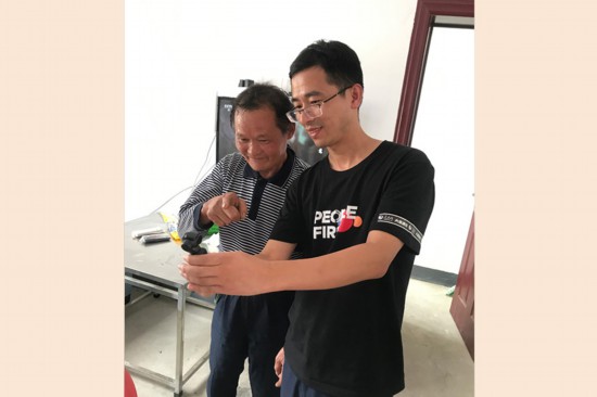 人民网记者在向汉中市鲁家坝村一位聋哑老人展示云台相机。人民网邓楠摄