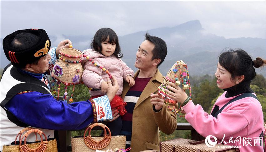 游客明英（右一）一家人在为女儿试羌族手工编织品小背篓。黎德华摄