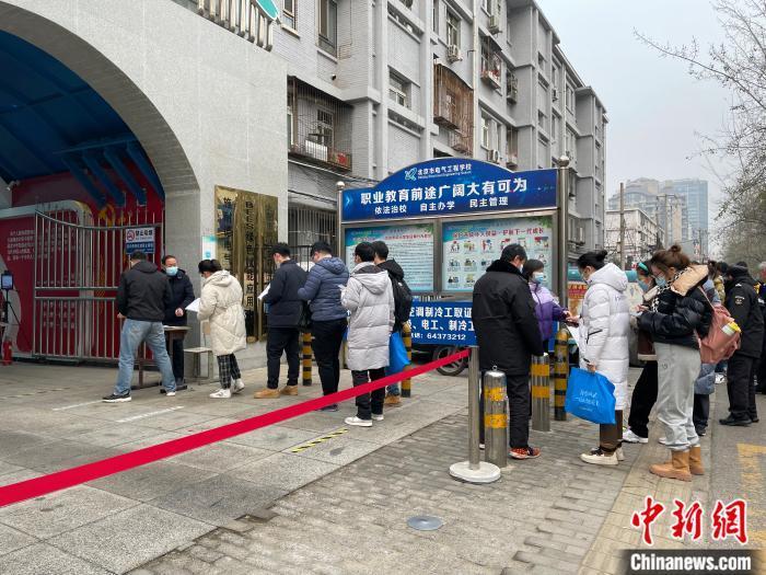 资料图：北京一考点外，考生正在排队进入考场。