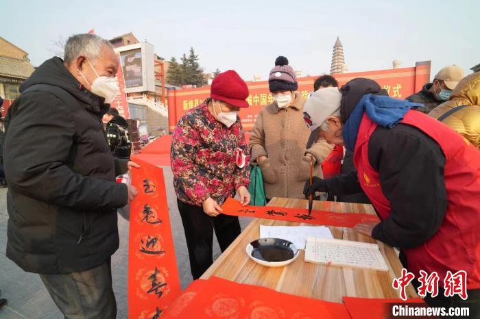 围观民众可挑选自己喜欢的春联，或者现场“私人订制”心仪的春联。 武俊杰 摄