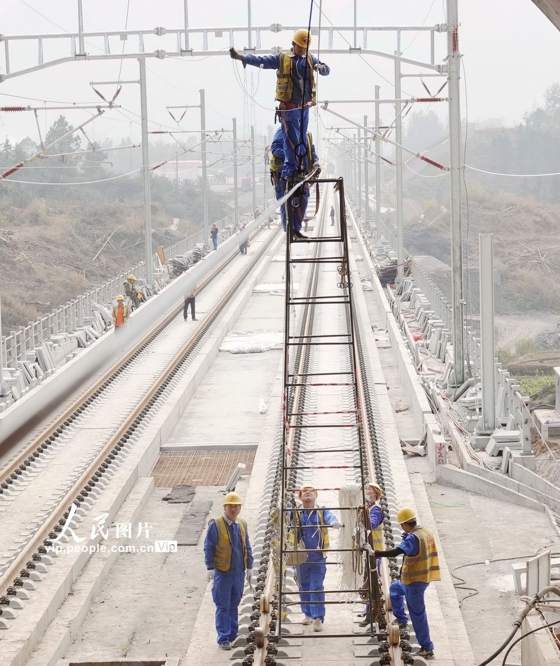 3月10日,贵南高铁广西段接触网完成架线后,施工人员在在替换接触网导线滑轮。