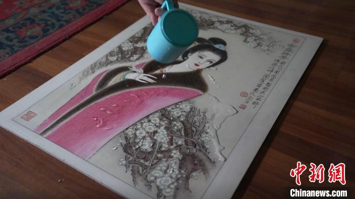 蔺烈演示在板刻线画作品上做防水试验,展示作品不仅防水还不掉色,湿水后还可用布擦拭。 戎睿 摄 蔺烈演示在板刻线画作品上做防水试验,展示作品不仅防水还不掉色,湿水后还可用布擦拭。 戎睿 摄