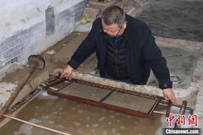 图为马永旗正在捞纸。 李一璠 摄