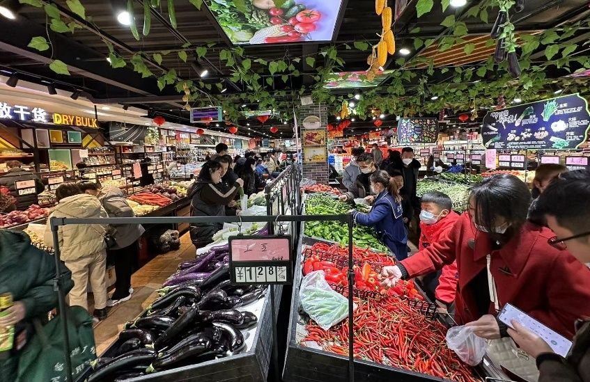 超市内顾客买年货，一派热闹景象。