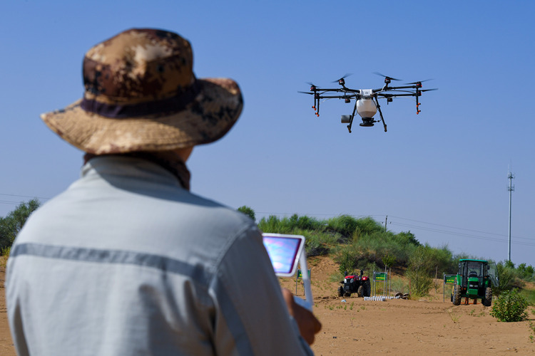 A technician controls a drone to sow seeds at the Kubuqi Desert, north China's Inner Mongolia Autonomous Region, July 11, 2018. (Xinhua/Peng Yuan)