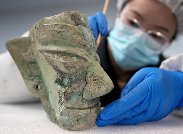 A restorer cleans a bronze mask at Sanxingdui Museum in Guanghan City, southwest China's Sichuan Province, Dec. 18, 2024. (Xinhua/Wang Yuguo)