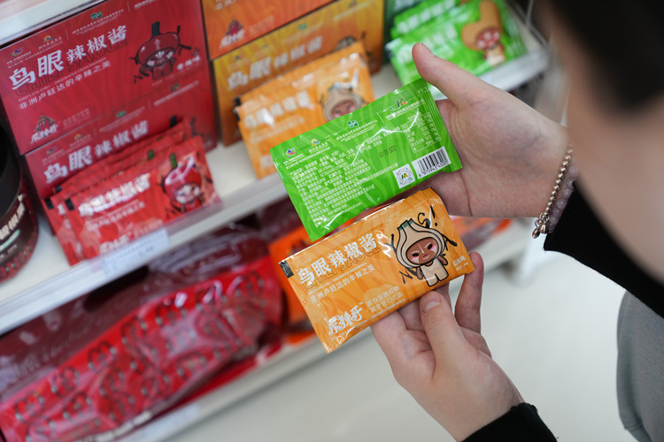 A consumer chooses Rwandan chili sauce products at a convenience store in Changsha, central China's Hunan Province, June 6, 2025. (Xinhua/Chen Zeguo)