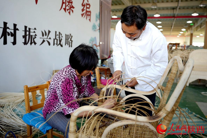 陈良顺（右）正在教授工人藤编技艺。人民网记者 邹星摄
