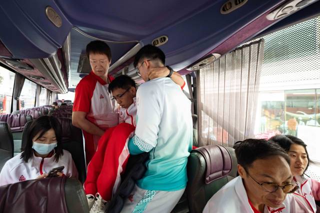 出发前,助教张健忠将行动不便的队员们逐一抱上大巴。 出发前,助教张健忠将行动不便的队员们逐一抱上大巴。