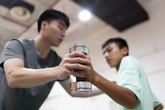 在结束早午两操后,助教林琪深单独留下钟英杰,帮助他用哑铃加练手臂伸展力量。 在结束早午两操后,助教林琪深单独留下钟英杰,帮助他用哑铃加练手臂伸展力量。