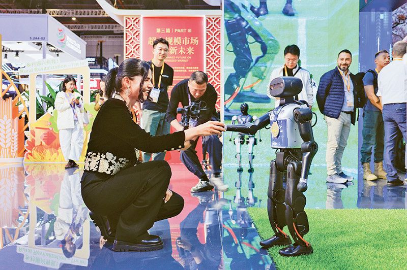 2025年11月5日至10日，第八届中国国际进口博览会在上海举办。图为11月5日，在第八届进博会国家展中国馆，一名外国参展商和机器人握手。据了解，本届进博会上，中国馆全面展示我国“十四五”期间全面深化改革、推进高水平开放的最新成就，众多科技成果引人瞩目。新华社记者 刘佳琪 摄