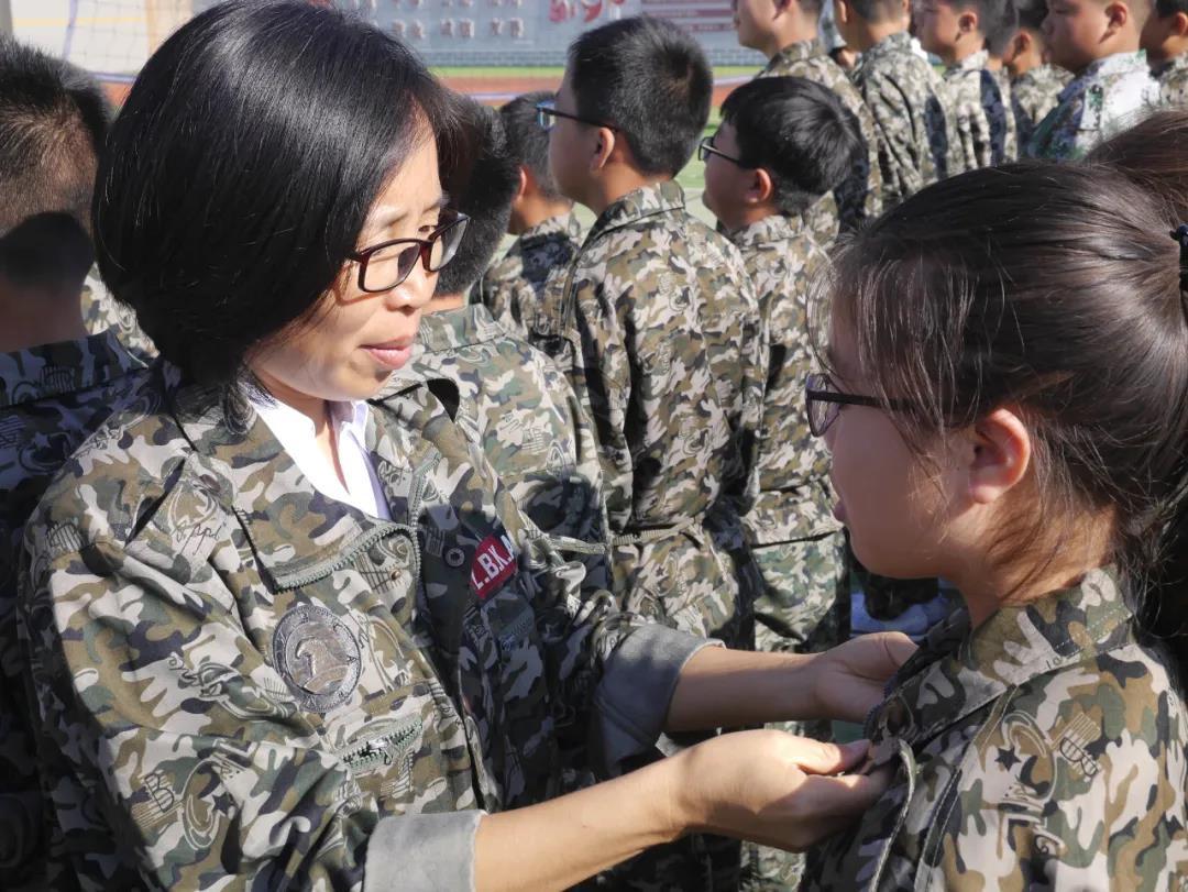 陕西韩城新城区第四初级中学教师许军玲(左一)为军训学生整理着装